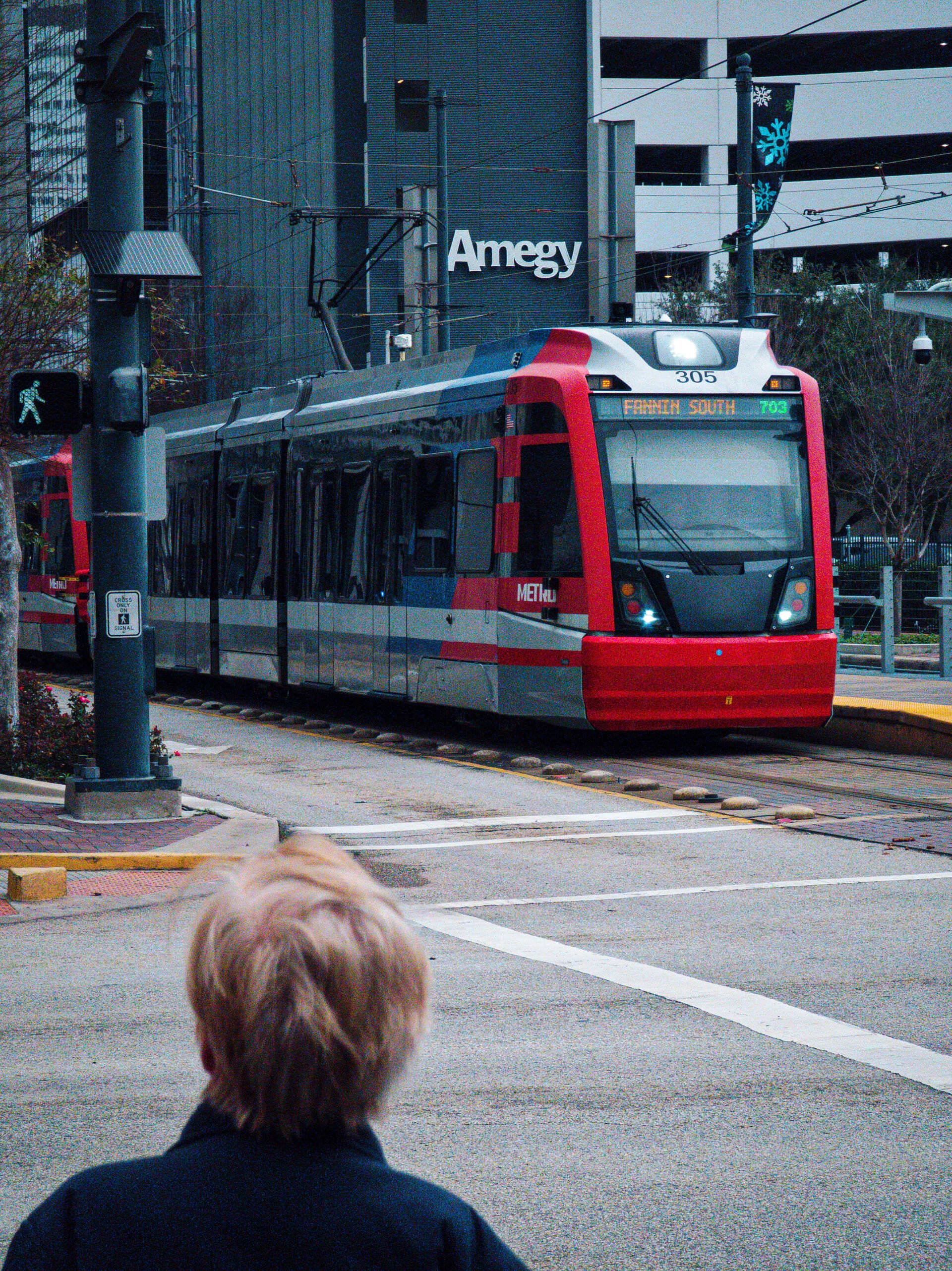 METRORail — Red and Silver Train Approaching Street Intersection in Houston