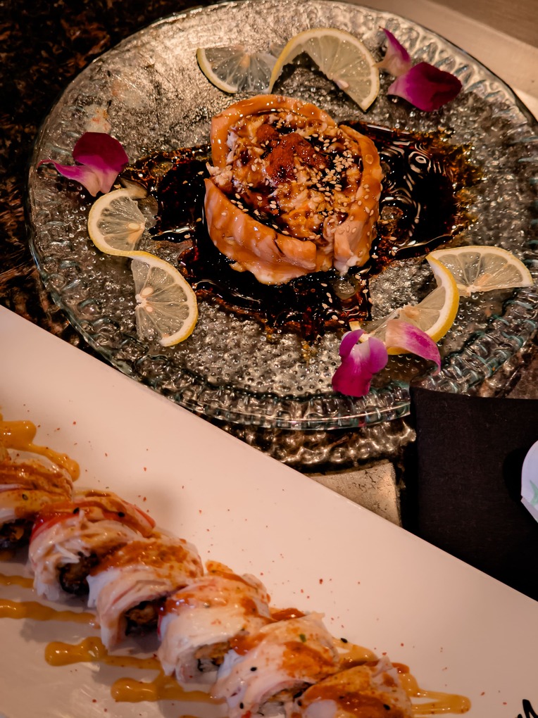 Culinary Display — Sushi Rolls with Sauce and Lemon Garnish on Minimal Plate